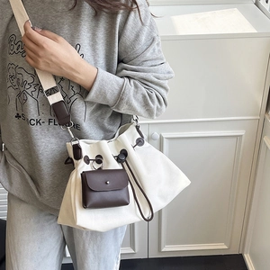 Dettaglio borsa a secchiello in tela crema con pochette in pelle e tracolla larga regolabile