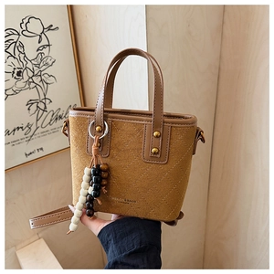 Détail d'un sac seau vintage en daim marron avec surpiqûres en losange et pendentif perlé