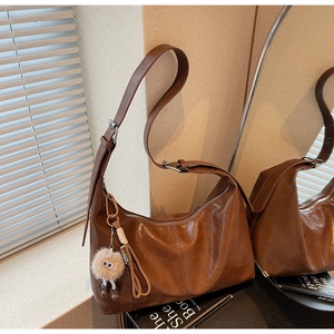 Détail d'un sac hobo rétro en cuir marron avec un porte-clé en peluche original