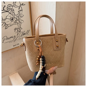 Détail du sac seau en daim beige avec surpiqûres matelassées et breloque en perles