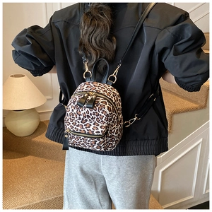 Rear view of a model wearing the mini leopard print backpack with gold zippers