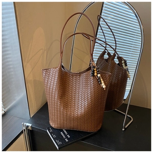 Close-up of brown woven tote bag featuring a colorful beaded tassel and mirror reflection