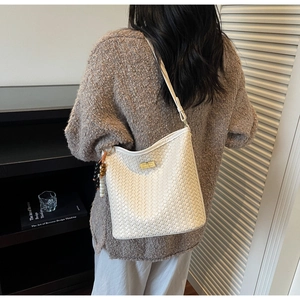 Detailansicht der weißen geflochtenen Hobo-Tasche mit goldenem Drehverschluss und Quaste