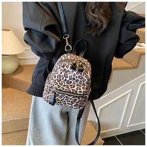 Detail view of mini leopard print backpack featuring golden zippers and slim black straps