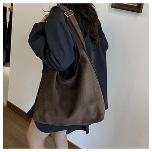 Detail of a large brown suede hobo bag featuring a wide strap and gold metal buckle