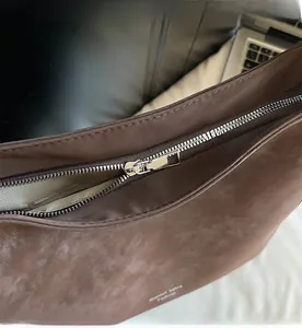 Detail of silver metal zipper and herringbone lining on large brown shoulder bag