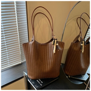 Detail of woven leather tote bag with stylish wooden bead charm and long shoulder strap