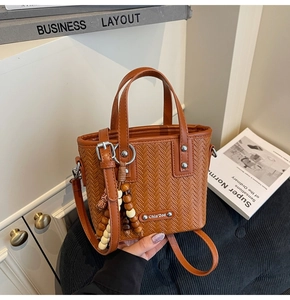 Détail de la texture tressée du sac seau marron avec gland décoratif en perles de bois