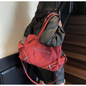 Detail of red large capacity tote bag with metal buckles and multi-pocket design