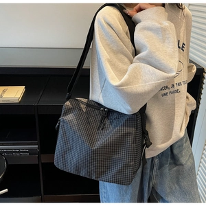 Detailed close-up of the black and grey checkered crossbody bag with adjustable strap