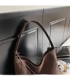 Detail of a brown suede hobo bag with a decorative knot handle hanging in an office setup