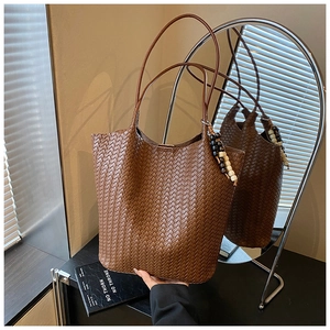 Detailed close-up of dark brown woven tote bag with artistic wooden bead accessory