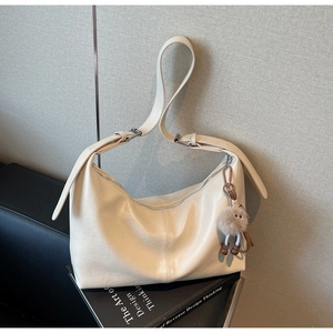 Sac hobo crème avec breloque monstre en peluche sur un livre de design artistique