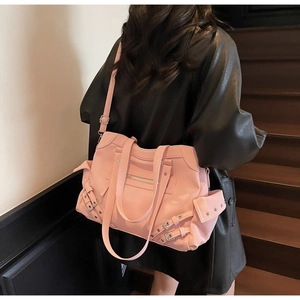 Détail du sac rose avec multi-poches et sangles à œillets métalliques porté par le mannequin