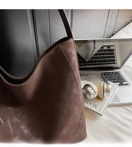 Close-up of brown suede tote bag featuring soft fabric texture and wide shoulder strap