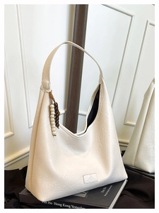 Gros plan du sac fourre-tout beige avec cuir plissé doux et pendentif décoratif en perles