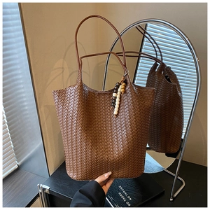 Detailed weave pattern on a brown leather tote bag with wooden bead charm accessory