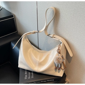 Détail du grand sac hobo crème en cuir brillant avec un charme en peluche monstre