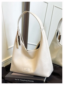 Détail du sac Hobo blanc cassé avec texture litchi et perles de bois décoratives