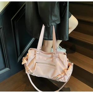 Detail of pink vintage tote bag showing decorative buckles and nylon texture on stairs