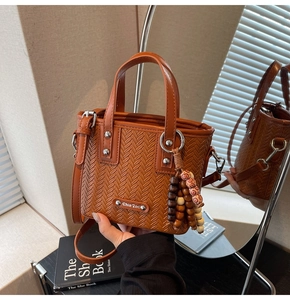 Détail de la texture tressée marron du sac avec breloque en bois et boucles en métal