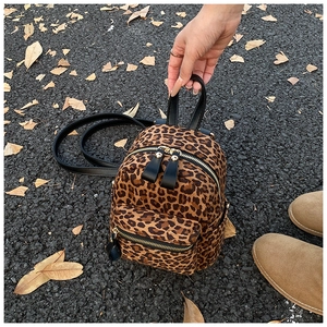 Detail of leopard print backpack with gold metal zippers and black leather handle