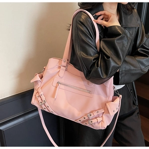 Detail of matte pink moto-style tote bag featuring metallic zipper and studded strap details