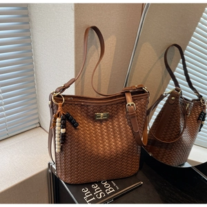 Detail der braunen geflochtenen Beuteltasche mit Metalldrehverschluss und Perlenanhänger