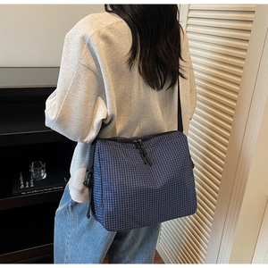 Detail of navy blue plaid canvas tote bag with adjustable shoulder strap and double zippers