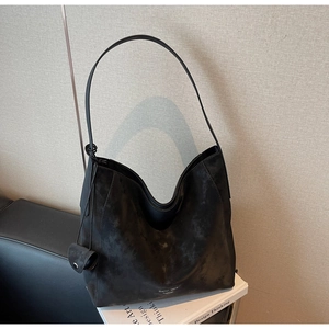Detail view of large black hobo bag with matte leather texture resting on design books