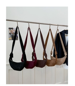 Détail de cinq sacs bandoulière en demi-lune avec texture matelassée sur un support