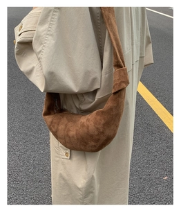 Détail du sac croissant en daim marron montrant la texture fine et les nœuds déco