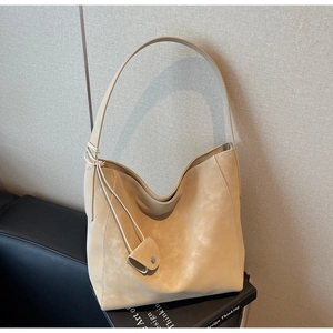 Detail of minimalist beige suede tote bag with knot strap and mini coin pouch accessory