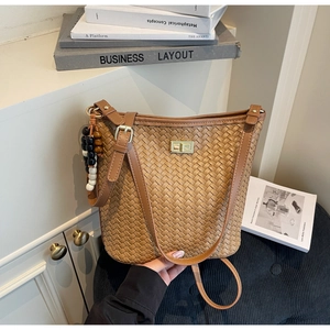 Detailansicht der geflochtenen Bucket Bag mit goldener Schließe und Perlenanhänger