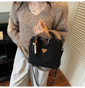 Détail du sac seau noir mat avec logo triangle doré et perles de bois ethniques colorées