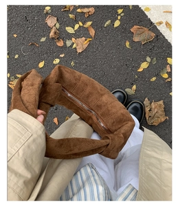 Détail d'un sac en daim marron avec poignée à nœud large et fermeture éclair en métal argenté