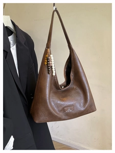 Détail du sac hobo vintage marron avec écusson logo et pendentif perles bois