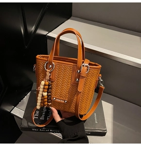 Gros plan sur le sac à main marron tissé avec pendentif en perles et détails métalliques
