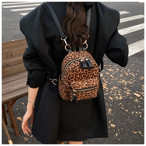 Outdoor shot of a mini leopard print backpack with gold hardware worn by a model