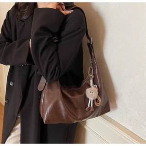 Brown vintage soft leather hobo bag featuring a cute plush eye charm on the shoulder strap