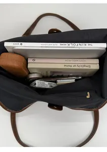 Top view of spacious interior of a black tote bag holding a laptop and books
