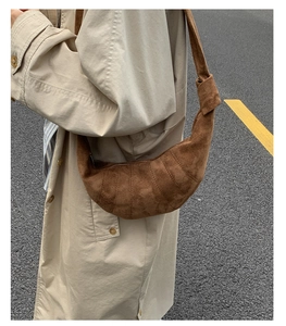 Détail du sac croissant en daim marron avec coutures incurvées segmentées distinctives