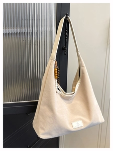 Détail du sac hobo beige givré avec large bandoulière et pompon décoratif en perles de bois
