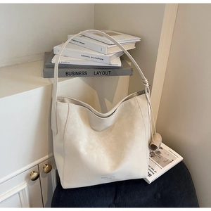 Detailed view of cream leather tote bag with matte texture and minimalist wide strap