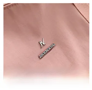 Gros plan sur la texture en tissu Oxford rose et le logo métallique d'un grand cabas