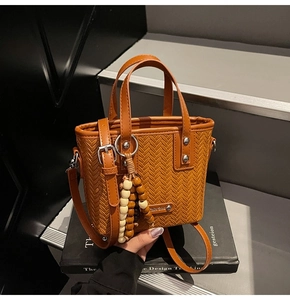 Détail de la texture tressée du sac seau marron avec pendentif en bois et boucles