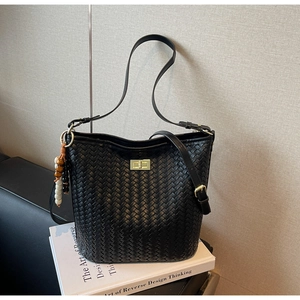 Details der schwarzen gewebten Beuteltasche mit goldenem Drehverschluss und Perlenanhänger