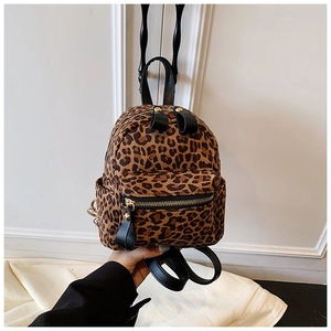 Detail of vintage leopard print backpack featuring black leather straps and gold zippers