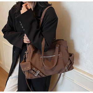 Fashionable dark brown large tote bag with decorative straps shown on a model