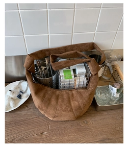 Détail montrant la grande capacité de rangement du sac croissant en daim marron foncé
